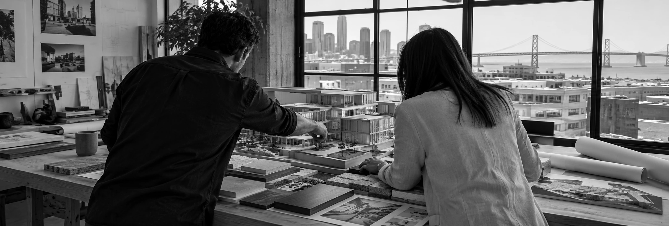 A designer and business owner discussing the project beside a detailed architectural model.