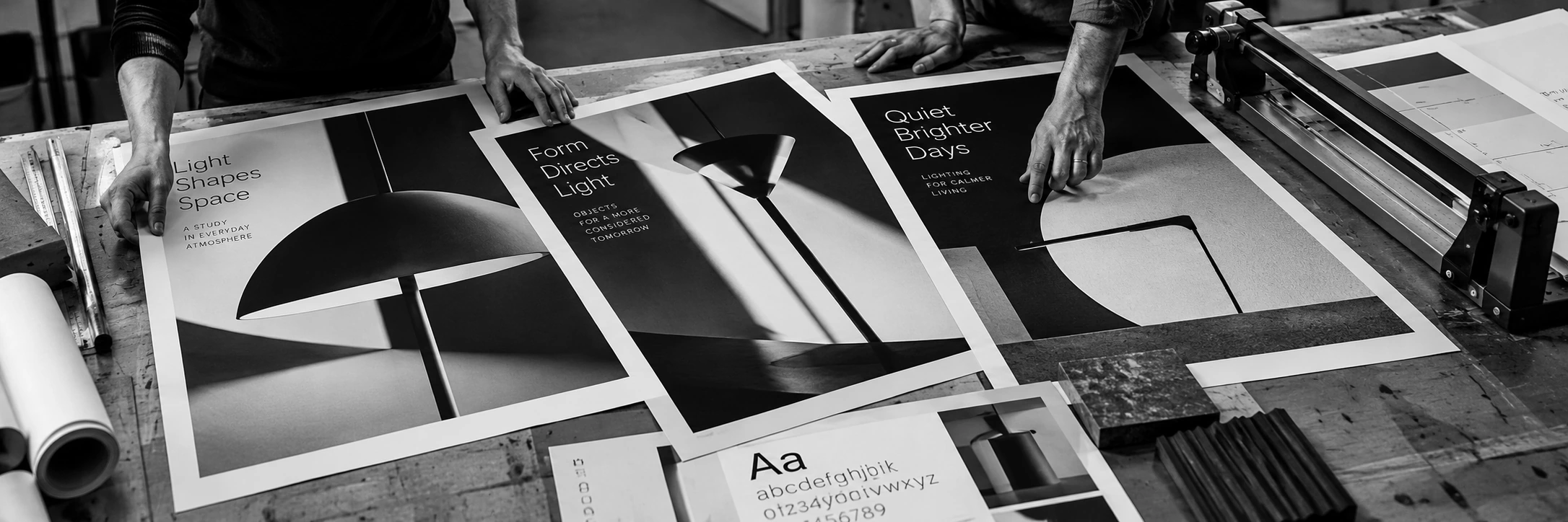 Working hands comparing distinct printed campaign directions on a studio table.