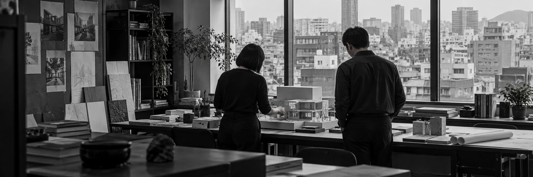 An architecture team reviewing a building model in a city studio, seen from behind.