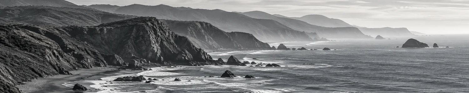 A black-and-white panorama of California’s rocky Pacific coastline.